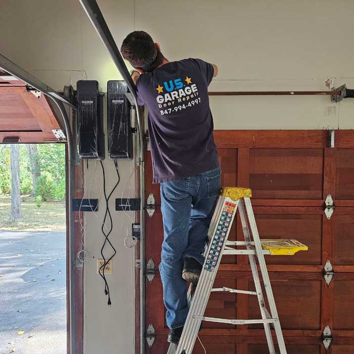 Professional Garage Door Repair near Buffalo Grove, IL US Garage Door Technician standing on the ladder and fixing garage door near Buffalo Grove, IL