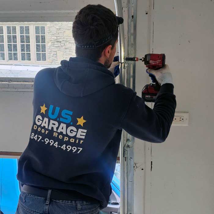 Professional Garage Door Repair & Installation Services Near Lake Zurich IL Our US Garage Door Repair technician using a battery-powered screwdriver to finish installing a track on a brand new garage door in Lake Zurich, IL