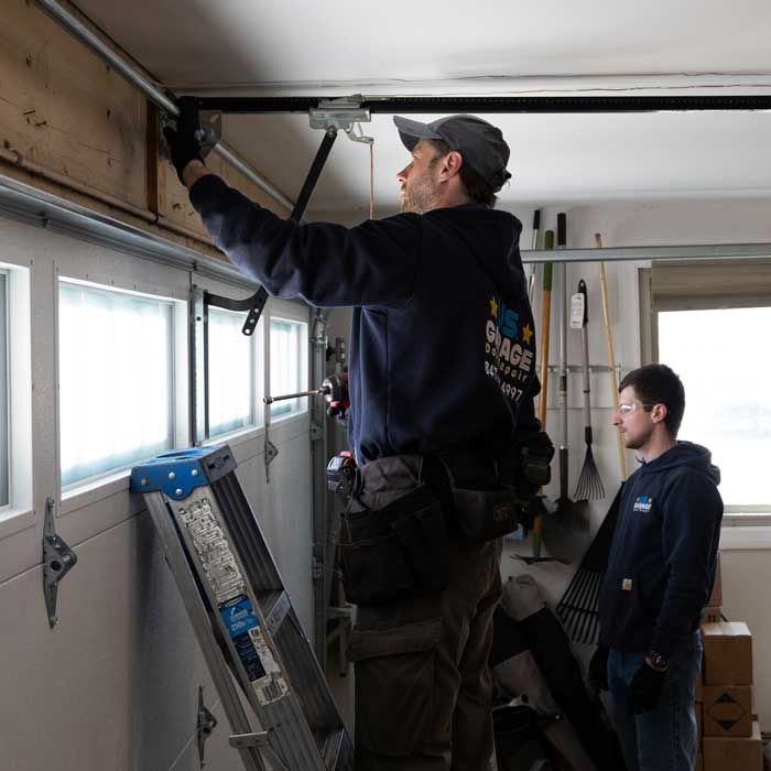 US Garage Door Repair technicians fixing a broken garage door spring near Schaumburg, IL